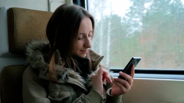 Nachdenkliche-Frau-im-Zug-unterwegs-und-per-smartphone