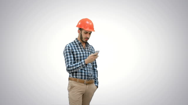 Young-manager-in-helmet-using-mobile-phone-on-white-background