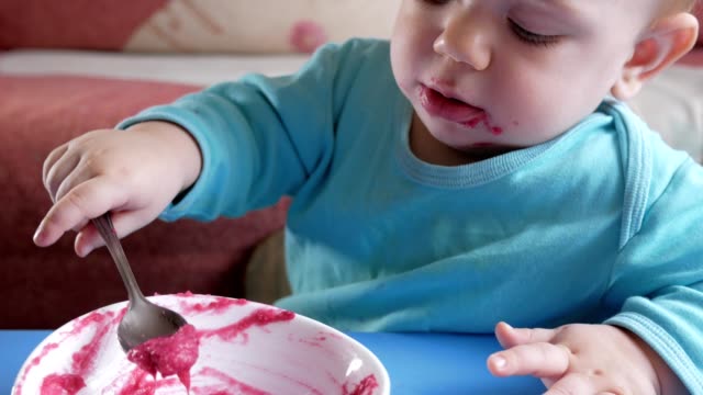 An-attractive-boy-2-years-old-eats-a-red-beet-salad.-The-face-is-smeared-with-porridge.-Sits-on-the-table