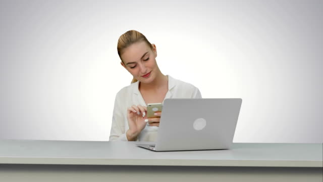 Happy-woman-is-dancing-on-her-own-using-smartphone-at-work-place-on-white-background