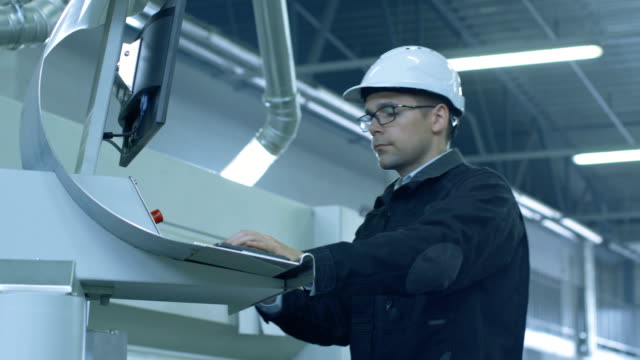 Ingenieur-in-Schutzhelm-Einrichten-von-CNC-Maschine-in-der-Fabrik