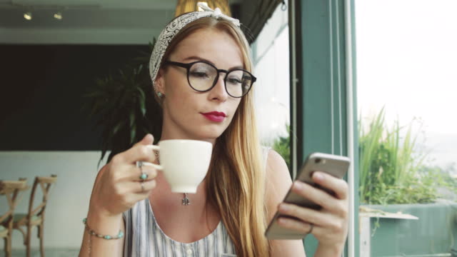 Beautiful-young-girl-texting-on-mobile-phone.-Woman-using-messanger-on-smartphone-in-cafe-and-smiling.