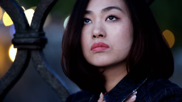 Outdoor-Closeup-Portrait-besorgt-und-nachdenklich-30er-Jahre-chinesische-Frau,-in-der-Nacht