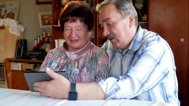 Una-pareja-de-ancianos-se-comunica-con-su-nieto-por-video-a-la-tableta.-Un-hombre-y-una-mujer-están-hablando-a-familiares