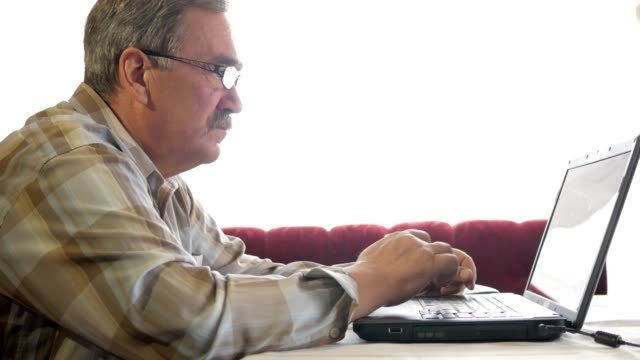 Senior-hombre-gafas-trabaja-para-un-ordenador-portátil.-En-serio-mira-el-monitor