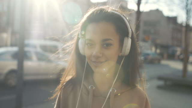 Mujer-joven-con-auriculares-disfrutando-en-una-ciudad.