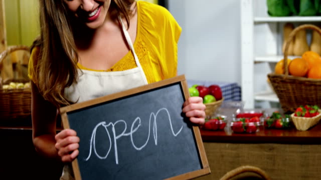 Portrait-of-female-staff-holding-a-open-sign