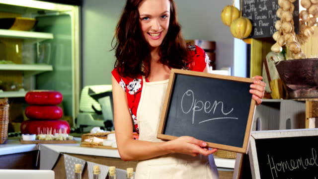 Portrait-of-a-female-staff-holding-a-open-sign