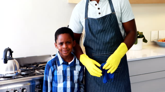 Smiling-father-and-son-standing-together-in-kitchen