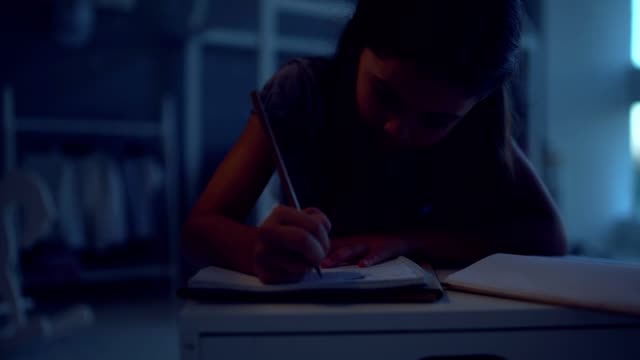 Pleasant-little-girl-doing-her-home-work-in-the-evening-at-home