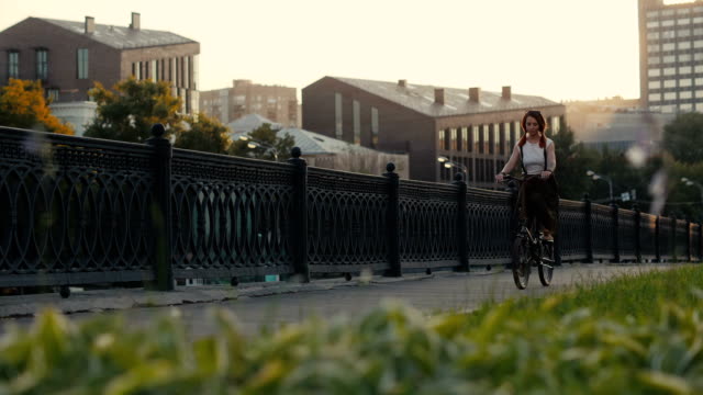 Bicicleta-de-mujer-de-cabello-rojo-a-caballo-en-la-ciudad-en-edificio-de-fachada-de-fondo