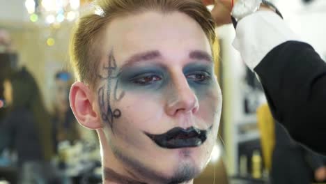 Artista-de-aplicar-el-maquillaje-de-halloween-en-la-cara-del-modelo-masculino.