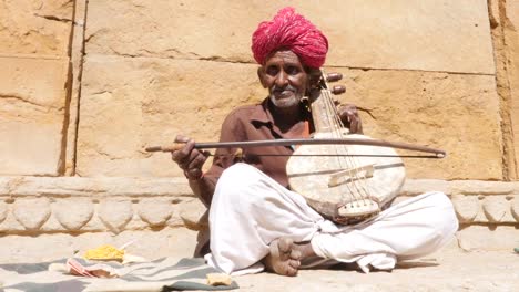 Senior-indio-toca-instrumento-musical-tradicional-en-el-fuerte-de-Jaisalmer,-Rajasthan,-India