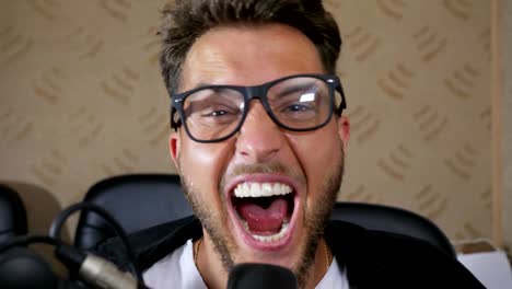 crazy-male-in-eyeglasses-with-wide-open-mouth-screams-into-microphone-at-recording-studio