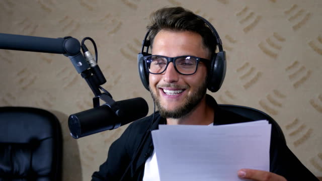radio-presenter-in-glasses-and-headphones-speaks-into-microphone