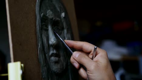 Nahaufnahme-des-Bildhauers-erstellen-Skulptur-des-menschlichen-Gesichts-auf-Leinwand-im-Atelier