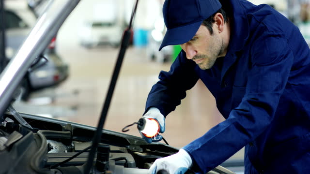 Specialist-auto-mechanic-in-the-car-service,-checks-the-car,-engine,-engine,-carburetor.-Concept:-repair-of-machines,-fault-diagnosis,-repair-specialist,-technical-maintenance-and-on-board-computer.