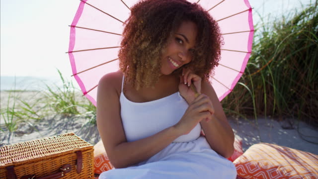Porträt-des-afroamerikanischen-Frauen-picknicken-am-Strand