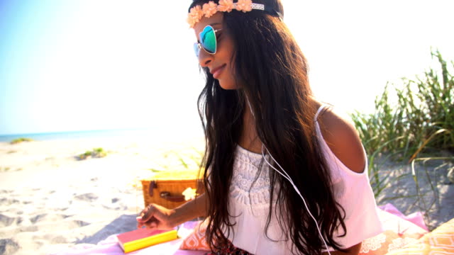 Indian-American-female-listening-music-at-beach-picnic