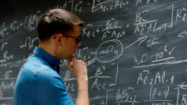 Brillante-junge-Akademiker-beendet-schreiben-große-und-komplexe-mathematische-Formel-/-Gleichung-an-die-Tafel.