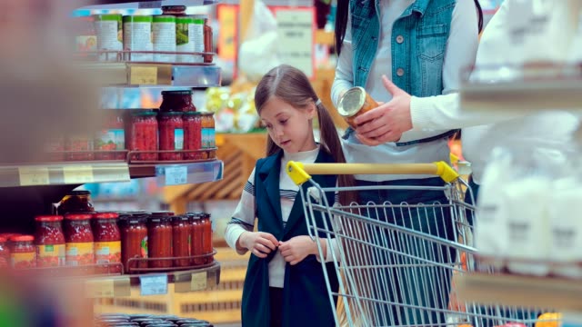 Porträt-eines-Mädchens,-der-wählt-Dosen-in-einem-Supermarkt-mit-ihrer-Familie