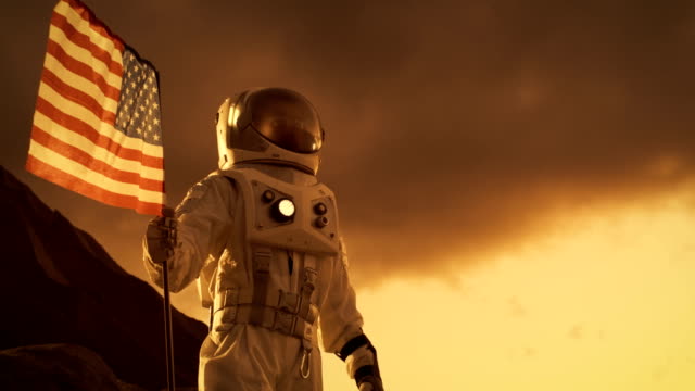 Astronaut-Raumanzug-tragen-Pflanzen-amerikanische-Flagge-auf-dem-roten-Planeten-/-Mars.-Patriotische-und-stolzer-Moment-für-die-ganze-Menschheit.-Raumfahrt-und-Kolonisierung-Konzept.