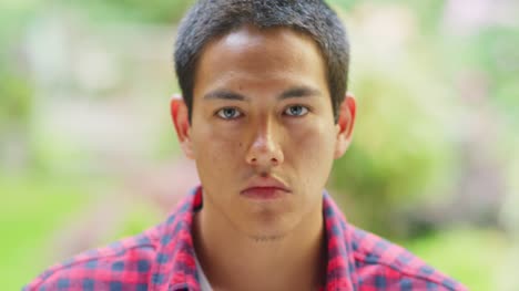 A-young-man-stares-intensely-in-front-of-a-camera,-portrait