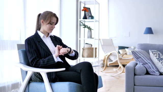 Frau-mit-Hilfe-Smartwatch-sitzend-auf-Sofa
