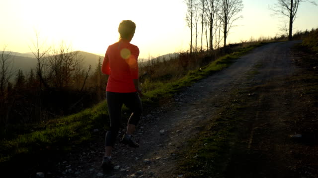 Junge-sportliche-Frau-läuft-im-Freien-bei-Sonnenuntergang-in-Berglandschaft.