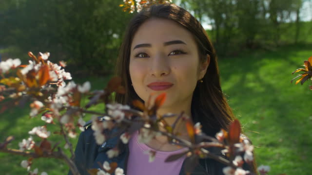 Junge-Asiatin-in-blühenden-Kirschbaum-Blüten-Garten
