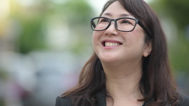 Reife-glücklich-schöne-asiatische-geschäftsfrau-denken-in-der-Straßen-Natur