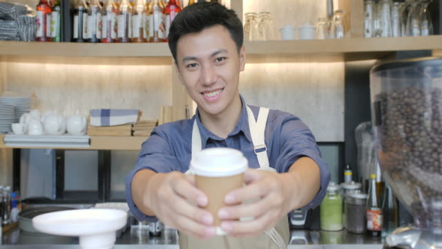 Coffee-Business-Concept---Beautiful-Caucasian-lady-smiling-at-camera-offers-disposable-take-away-hot-coffee-at-the-modern-coffee-shop