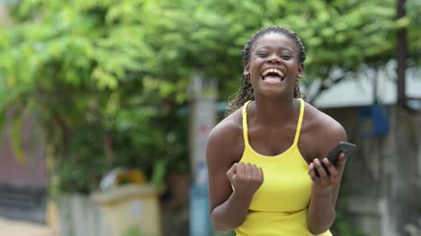 Junge-glücklich-Afrikanerin-mit-Telefon-im-freien
