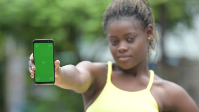 Glückliche-junge-Afrikanerin-mit-Telefon-im-freien