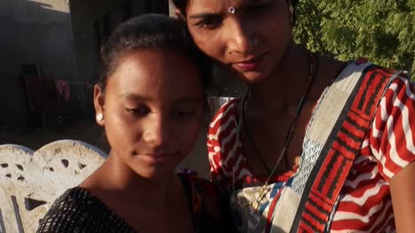 Tiro-mano-de-dos-hermosas-mujeres-felizes-alegres-foto-video-selfie-junto-con-un-teléfono-inteligente-ayudar-uno-al-otro-amor-de-la-vinculación-a-ayudar-a-medio-tiro-al-aire-libre-rural-India-Asia-del-sur
