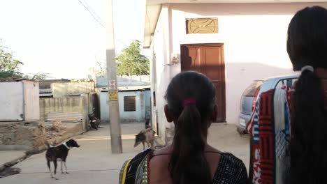 Zwei-Frauen-Hand-in-Hand-und-gehen-gemeinsam-zurück-geschossen-handheld-Mitte-Schuss-durch-Straßen-im-Dorf-Kleinstadt-Indien-Freunde-kleben-zusammen-glücklich-lachend-liebe-Pflege-Tracht-Straßen-im-freien