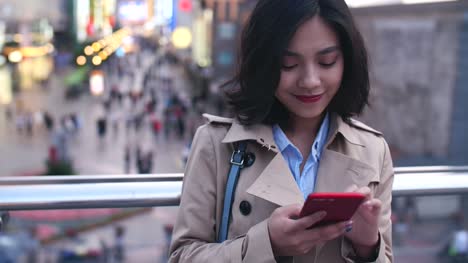Joven-mujer-asiática-usando-teléfono-inteligente-en-la-ciudad