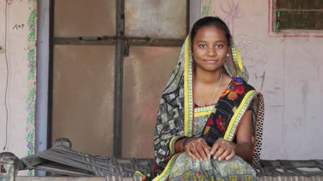 Mitte-Schuss-des-indischen-Teenager-Mädchen-sitzt-zu-Hause-mit-Sari-Kleid-anpassen-traditionelle-Namaste-Respekt-bedeckt-Kopf-Blick-in-die-Kamera-Henna-tätowiert-Hand-in-Hand-zur-Begrüßung-lächelnd-Inhalte-statisch