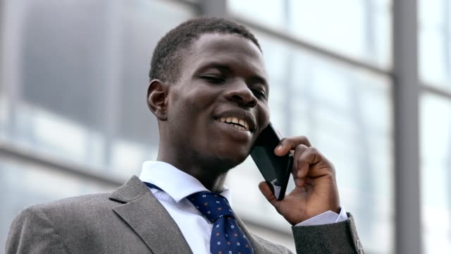 Lächelnde-schwarze-Business-Mann-Gespräch-per-Telefon-in-der-Straße