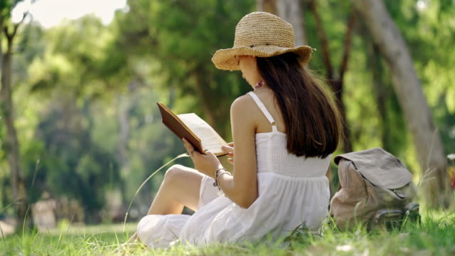 Young-woman-reading-a-book--outdoors