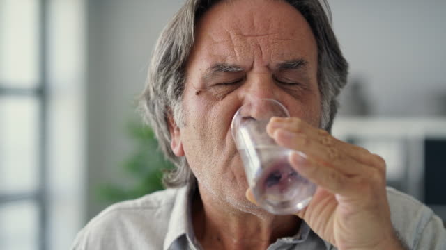 Alter-Mann-mit-empfindlichen-Zähnen-hält-ein-Glas-mit-kaltem-Wasser