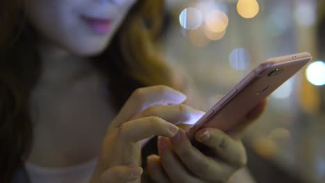 Junge-asiatische-Frau-mittels-Smartphone-in-die-Stadt-bei-Nacht