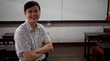 Portrait-of-young-handsome-Asian-male-teacher-smiling-inside-the-classroom