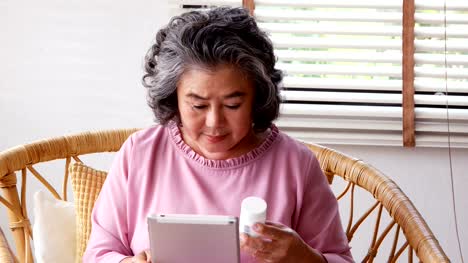 Senior-woman-Medikament-Flasche-in-der-hand-halten-und-suchen-Informationen-über-sie.-Menschen-mit-Gesundheits--und-medizinischen-Konzept.-4-k-Auflösung.