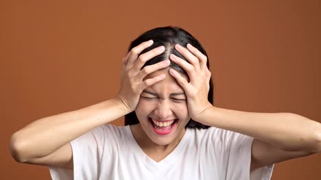Angry-woman-isolated.-Portrait-of-asian-woman-in-white-t-shirt-screaming-out-loud-looking-at-camera-and-hand-on-head.