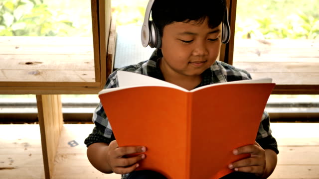 Cute-asian-children-reading-a-book-and-listen-to-music-at-home.-education-concept