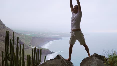 Fit-young-man-practices-sun-salutation-yoga-in-mountain-for-ocean.-Young-man-enjoying-meditation-and-yoga.-fitness,-sport,-people-and-lifestyle-concept---young-man-making-yoga-exercises.