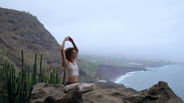 Frau-bei-Sonnenaufgang-auf-einem-Felsen-in-den-Bergen-meditieren.-Üben-Sie-Yoga-auf-outdoor.