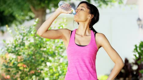 Portrait-ethnic-female-drinking-water-fitness-routine-outdoors