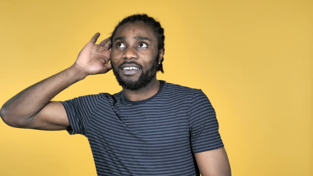 African-Man-Listening-Secret-Standing-Isolated-on-Yellow-Background